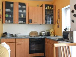 a kitchen with wooden cabinets and a stove top oven at Apartment in Bruchhausen right on the fishing river in Oberveischede