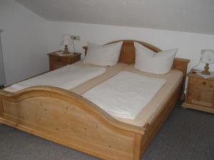 Apartment in the Allg u with view of the Bavarian Alps في Bernbeuren: سرير خشبي عليه أغطية ووسائد بيضاء
