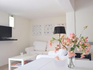 a white living room with a white couch and pink flowers at Apartment in Montbrun les Bains near forest in Reilhanette
