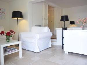 a living room with a white chair and a table at Apartment in Montbrun les Bains near forest in Reilhanette