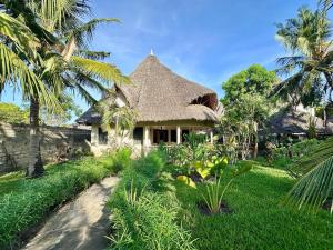 een huis met een rieten dak en een pad bij Villa Twiga in Ukunda