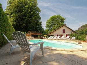 a swimming pool with chairs and a house at Appealing apartment in Vezac with swimming pool in Beynac-et-Cazenac