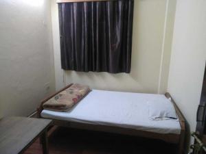uma pequena cama num quarto com uma janela em Hotel J P Lodge Kalimpong em Kalimpong