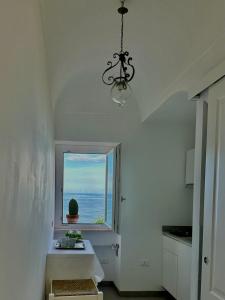 een witte keuken met een raam en een kroonluchter bij LA CASA SUL MARE in San Vito Chietino