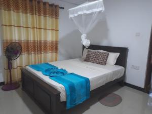 a bedroom with a bed with a blue blanket on it at The Cozy Cottage Habarana in Habarana