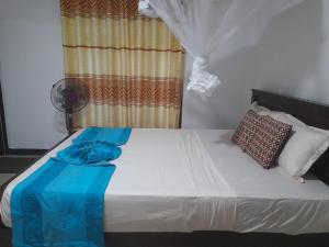 a bed with a blue blanket on top of it at The Cozy Cottage Habarana in Habarana