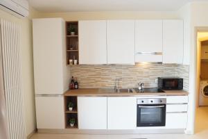 a kitchen with white cabinets and a sink and a microwave at Lake Como: Bellavista apartment in Bellano