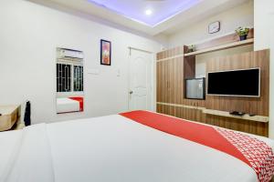 - une chambre avec un grand lit blanc et une télévision à écran plat dans l'établissement OYO OYO Emara Boutique Hotel Nearby Koramangala Forum Mall, à Bangalore