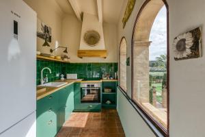 una cocina con armarios verdes y una ventana arqueada en El Pedró Panoramic, en Ventalló