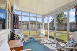 a screened in porch with chairs and a table at Witsend - Foxton Beach Holiday Home in Foxton Beach