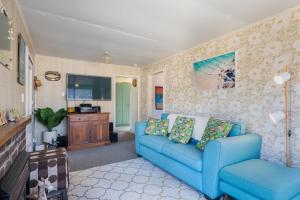 a living room with a blue couch and a tv at Witsend - Foxton Beach Holiday Home in Foxton Beach