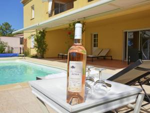 a bottle of wine sitting on a table next to a pool at Beautiful Villa in Vidauban with seasonal Pool in Vidauban