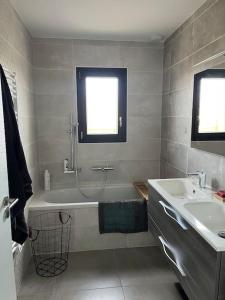 uma casa de banho com uma banheira, um lavatório e uma janela em Jolie maison avec piscine em Nissan-lez-Enserune