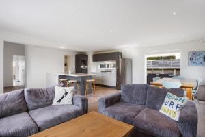 een woonkamer met 2 banken en een keuken bij Modern Kiwi Bach - Waihi Beach Holiday Home in Waihi Beach