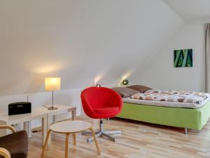 a bedroom with a bed and a red chair at Pleasant Holiday Home in Zierow near Sea in Zierow