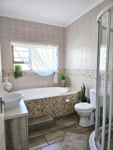 a bathroom with a tub and a toilet and a sink at Bliss on JBay - Blissful in Jeffreys Bay