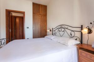- une chambre avec un lit blanc et une armoire en bois dans l'établissement Appartamento Torre San Giovanni, à Torre San Giovanni