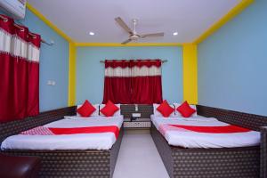 two beds in a room with red curtains at OYO Hotel Rajeswari in Rupnārāyanpur