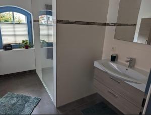 a white bathroom with a sink and a shower at Ferienwohnung Zur Kirschallee in Hochkirch