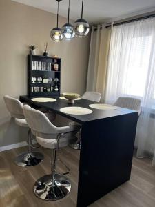 a kitchen with a black island with chairs and lights at Apartmán Artemis in Košice