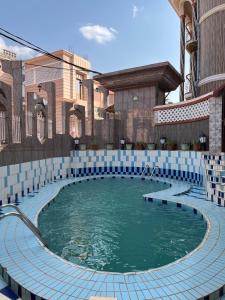 uma piscina num edifício com azulejos azuis e brancos em Farhyda & Frères Hôtels em Bangangté