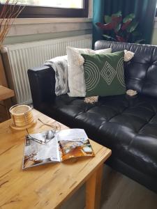 a living room with a black leather couch and a wooden table at Dom Górski Klimat-Willa 160 m2 z wewnętrzną sauną fińską, zniżki do Term Gorący Potok in Czerwienne