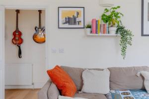 a living room with a couch and a guitar on the wall at Stylish Bohemian 2BD Flat Mile End Park! in London