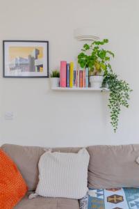 a shelf above a couch with books and a plant at Stylish Bohemian 2BD Flat Mile End Park! in London