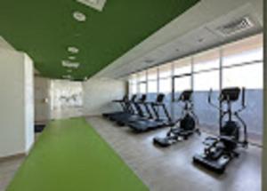 una sala de fitness con cintas de correr y máquinas elípticas en Aura Azizi by Golden Casa, en Dubái