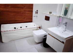 a bathroom with a tub and a toilet and a sink at Hotel The Grand Palace, Ghaziabad in Ghaziabad