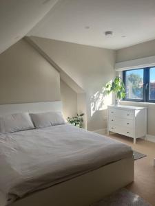 a bedroom with a bed and a dresser and a window at Splendid South Dublin Ranelagh Townhouse in Dublin