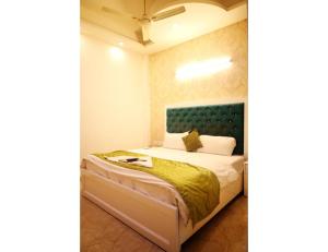 a bedroom with a bed with a blue headboard at Hotel The Grand Palace, Ghaziabad in Ghaziabad