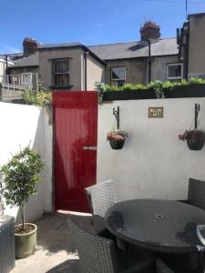 a red door on a white wall with a table and chairs at Splendid South Dublin Ranelagh Townhouse in Dublin