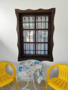 une table avec deux chaises jaunes et une fenêtre dans l'établissement ΔΙΑΚΟΠΕΣ ΣΤΗ ΘΑΣΟ ! ! !, à Theológos