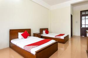 two beds with red pillows in a room at Cửa Đại Beach Hotel in Hoi An