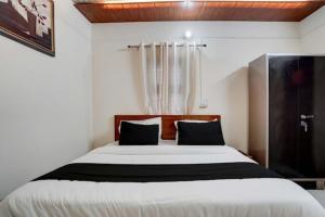 um quarto com uma grande cama branca com almofadas pretas em JMD 13 Hotel em Gurgaon