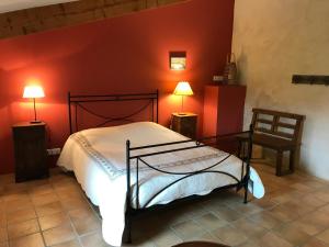 - une chambre avec un lit et un mur rouge dans l'établissement Gîte Le Mas du Colombeyras, à Espeluche