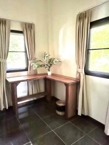 uma mesa num quarto com duas janelas e uma planta em Jungle Vibes em Thongsala