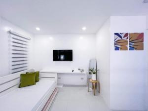 a white living room with a couch and a tv at Moonlight House Tagaytay in Tagaytay