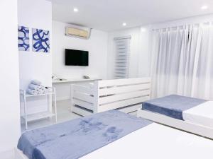 a white bedroom with two beds and a tv at Moonlight House Tagaytay in Tagaytay