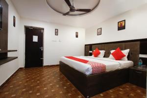 um quarto com uma cama grande e almofadas vermelhas em OYO Grand Beach Palace em Tirupporūr