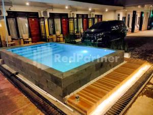 - une piscine dans une maison avec une voiture en arrière-plan dans l'établissement The Paragon Hotel Cilacap Redpartner, à Cilacap
