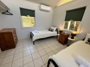 a room with two beds and a chair and two windows at Gindabara Coochiemudlo Island in Coochiemudlo