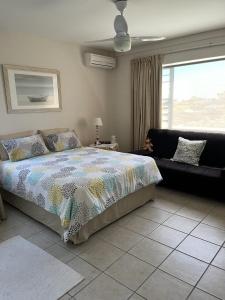 a bedroom with a bed and a couch and a window at 22 Lands End in Ballito
