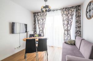 uma sala de estar com uma mesa e cadeiras e um sofá em Apartament 32 em Gąski
