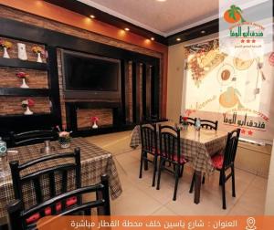 a dining room with tables and chairs and a television at Abo Elwafa Hotel in Sūhāj