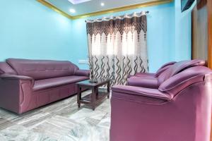 a living room with two purple couches and a table at Collection O Hotel Jaisas Paradise in Agastīswaram