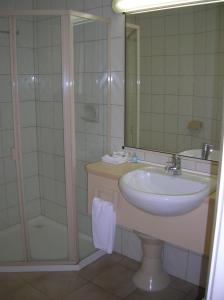 uma casa de banho com um lavatório e um chuveiro com um espelho. em Peninsula Motor Inn em Tyabb