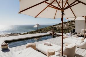 una piscina con sedie bianche e ombrellone e l'oceano di Pure Sea Boutique Lodge a Gansbaai