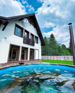 una casa con piscina frente a ella en Mountain Paradise & Wellness, en Izvoare